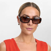 Woman wearing sunglasses and a red sleeveless top on a white background