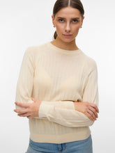 Woman wearing a beige sweater with a plain background