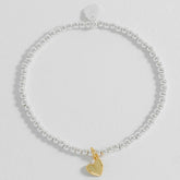 A gold-plated folded heart charm bracelet with white bead embellishments.