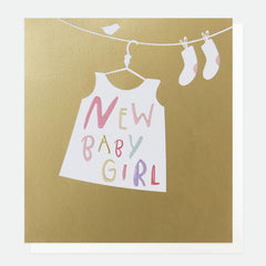 new baby girl' written on the skirt hanged on laundry holder. base gold