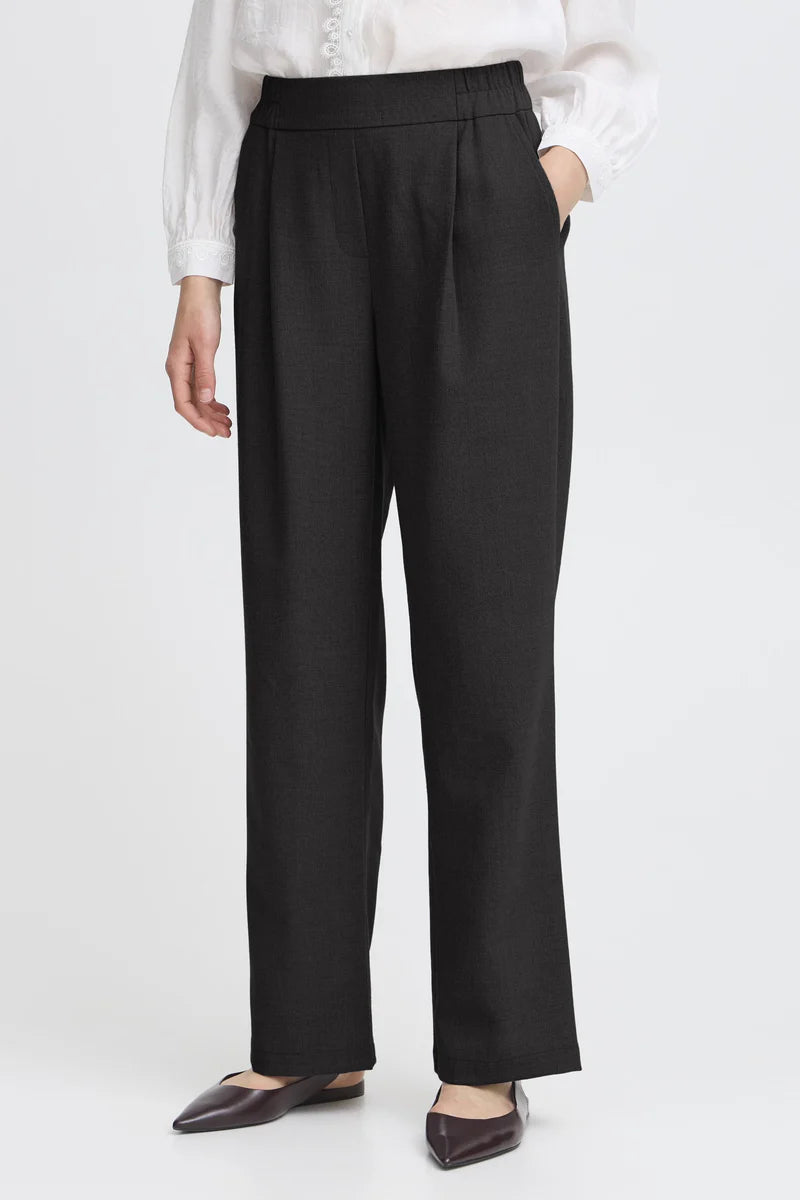 Person wearing black pants with a white shirt on a light gray background