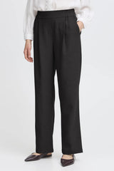 Person wearing black pants with a white shirt on a light gray background